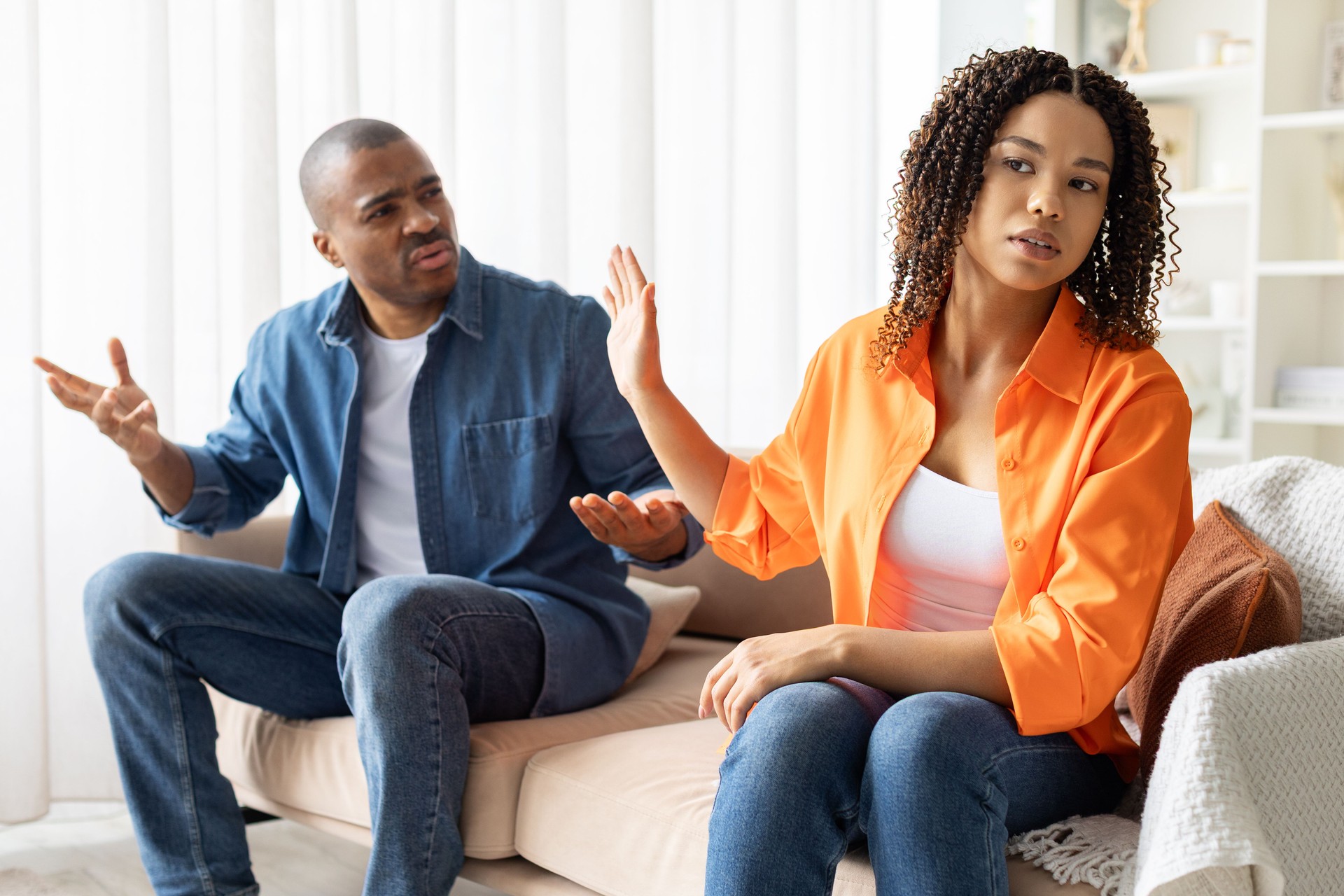 African American couple arguing at home, woman turning away with protest